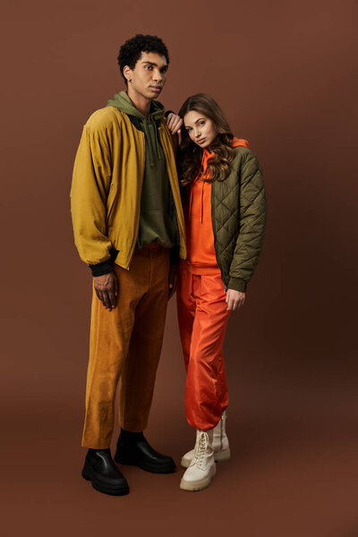 A stylish couple showcases trendy autumn outfits in rich, vibrant colors, exuding warmth.