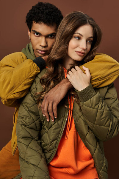 Модная пара с нетерпением обнимается, одетый в радостный осенний наряд, источая тепло и стиль.