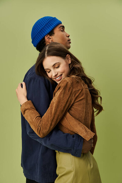 A fashionable couple celebrates the autumn season with joyful expressions and cozy attire.