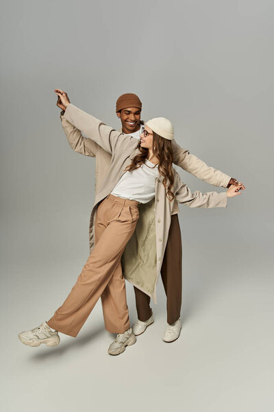 Модная пара радостно позирует в ярких осенних нарядах, олицетворяющих тепло и стиль.