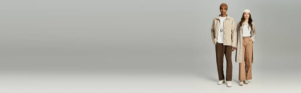 Стильная молодая пара уверенно стоит в осеннем наряде, излучая тепло и очарование.