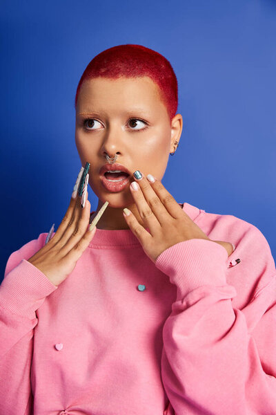 This young woman with short pink hair showcases her bold fashion sense in a creative studio environment.