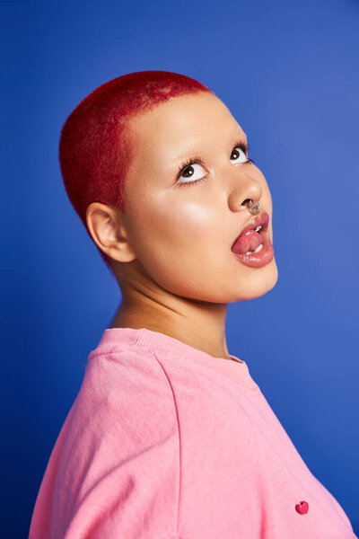 В студии молодая женщина с уверенностью демонстрирует свою яркую розовую прическу и смелый выбор моды.