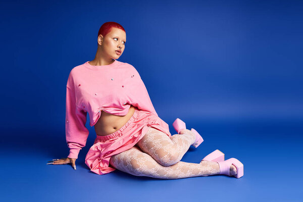 Уверенная в себе молодая женщина демонстрирует свой энергичный стиль в студии, демонстрируя уникальный, смелый взгляд.