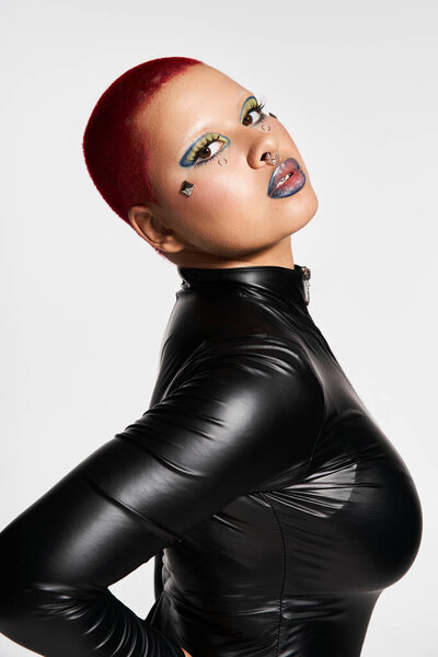 A young woman with vibrant pink hair and striking makeup showcases her unique fashion in a studio.