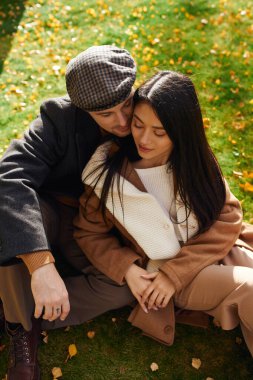 Bir çift açık havada sıcak bir anı paylaşıyor, renkli sonbahar yapraklarından oluşan bir yatakta birlikte..