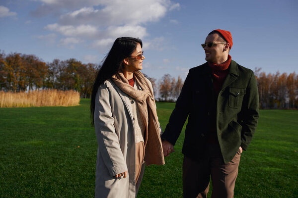 A charming couple enjoys a leisurely walk together, embracing the beauty of autumn.