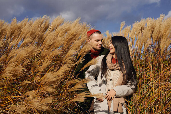 A loving couple enjoys a cozy moment together, surrounded by swaying autumn grass.
