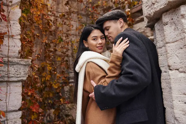 stock image A charming couple dressed in autumn layers enjoys a tender moment amidst colorful leaves.