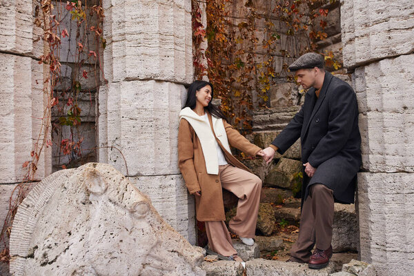 A couple enjoys a tender moment while surrounded by warm autumn colors and historic stone walls.