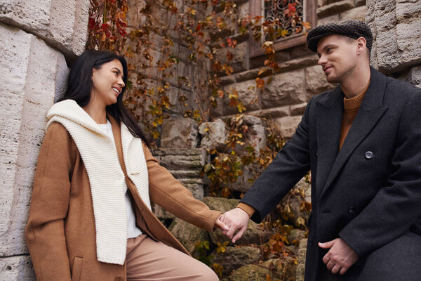 A couple shares a tender moment, warmly dressed against the autumn chill, surrounded by nature.