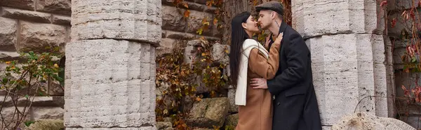 stock image A couple shares a tender kiss, cozy in fall outfits amid natures beauty.