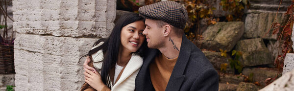 A happy couple in cozy autumn outfits enjoys their love amidst vibrant fall colors.