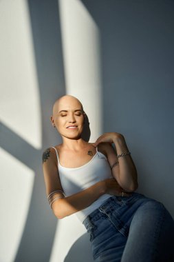Alopecia hastası genç bir kadın, yumuşak doğal ışıkta dinlenirken kendine güvenini sergiliyor..