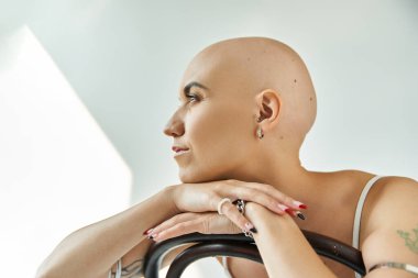 Alopesia hastası genç bir kadın özgüven ve zarafet gösteren bir sandalyeye uzanıyor..