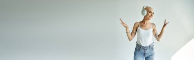 Alopecia hastası genç bir kadın, minimalist bir mekanda müziğinden zevk alırken mutluluk saçar..