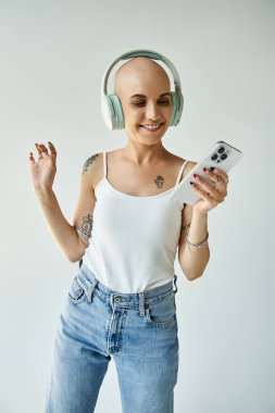 Alopecia 'lı genç kadın müzik dinlerken ve telefonunu kontrol ederken neşe saçıyor..