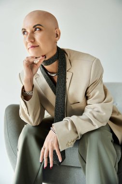 Kendine güveni olan genç bir kadın düşünceli bir şekilde oturur ve kişiliğini ve tarzını ön plana çıkarır..