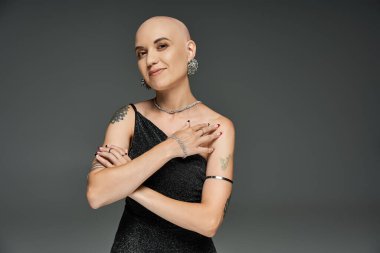 Saçları dökülmüş genç bir kadın zarifçe poz veriyor, güç ve zarafet saçıyor..