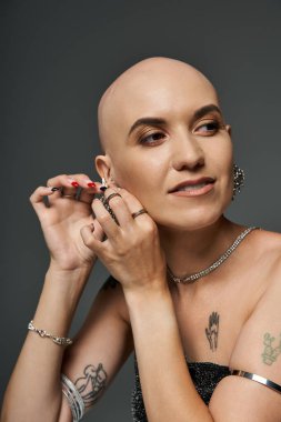 Kendine güvenen, kel bir kadın, saç dökülmesi ustalıkla küpe takar ve tarzını gösterir..