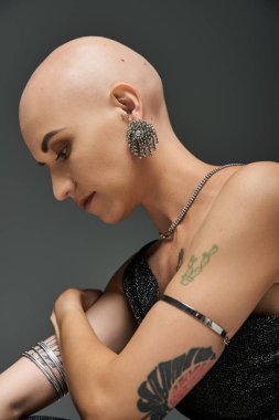 Çarpıcı genç bir kadın, tıraşlı kafasını ve kalın dövmelerini sergiliyor, kendine güven ve zarafet saçıyor..