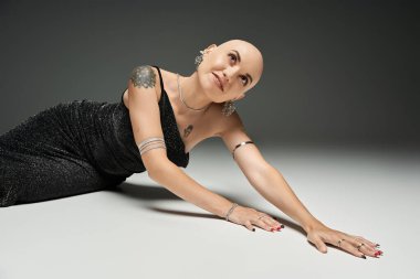 A young bald woman showcases confidence and elegance while striking a captivating pose. clipart