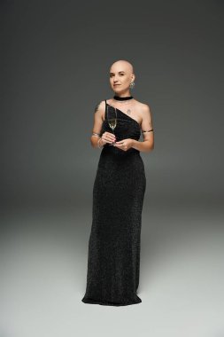 Alopecia 'lı genç kel bir kadın zarif bir şekilde elinde bir bardak, kendine güveni ve zarafeti ile ayakta duruyor..