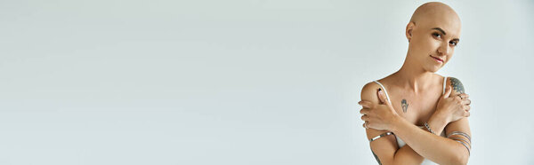 Молодая лысая женщина с алопецией выражает свою индивидуальность и силу, излучая красоту.