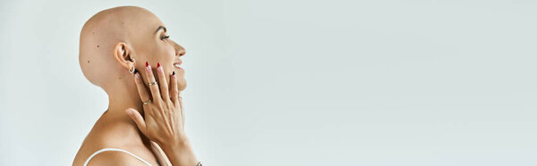 A young bald woman gracefully embraces her alopecia while smiling joyfully.