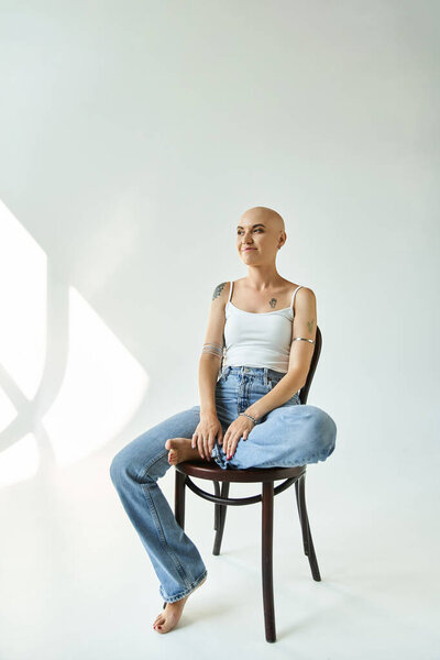 Молодая лысая женщина излучает уверенность в себе, когда она изящно позирует в мягком свете.