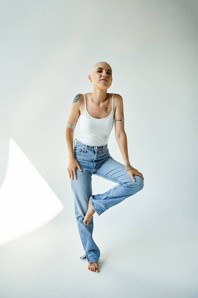 Молодая лысая женщина демонстрирует свою уверенность, творчески позируя в современной студии.