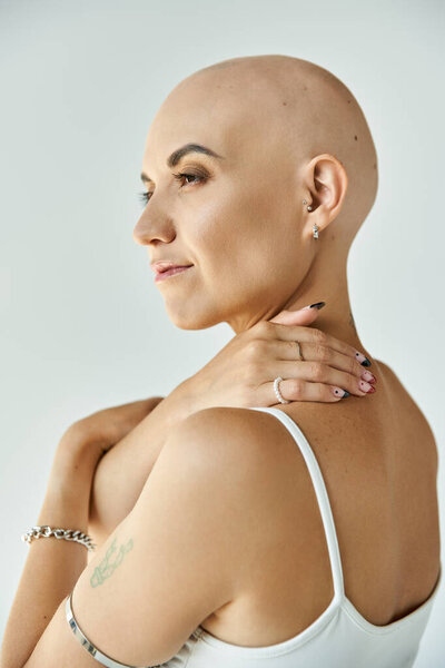Молодая лысая женщина обнимает свою алопецию элегантно, подчеркивая свою уверенность и силу.