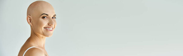 Уверенная в себе молодая женщина с алопецией тепло улыбается, радуясь своей неповторимой красоте..