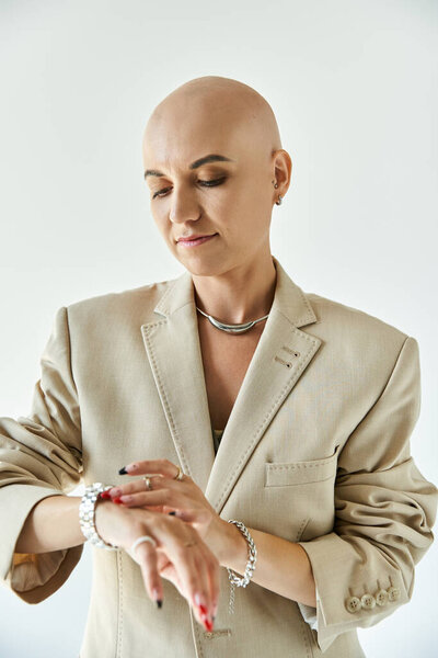 A young bald woman embraces her beauty while checking her watch, radiating confidence.