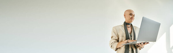 A confident young bald woman engages with her laptop, radiating focus and creativity.