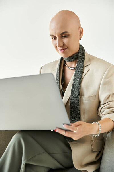 Уверенная лысая женщина с алопецией фокусируется на ноутбуке, излучая грацию и самообладание..