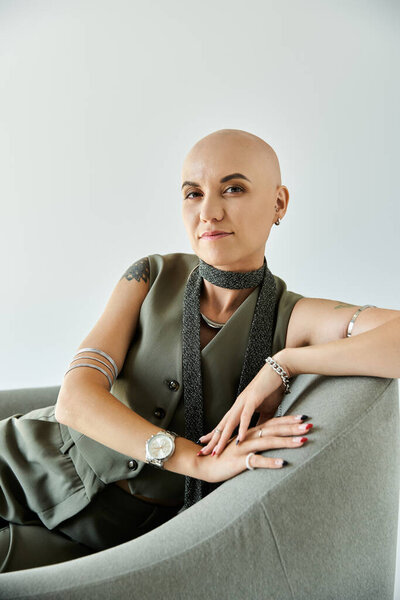 Молодая лысая женщина выражает уверенность в себе, расслабляясь в современном кресле.