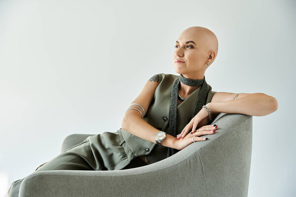 Молодая женщина с алопецией излучает уверенность, изящно отдыхая в современном кресле.