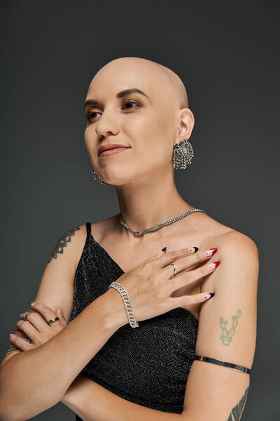 A bold young woman confidently displays her alopecia, adorned with stylish jewelry and attitude.