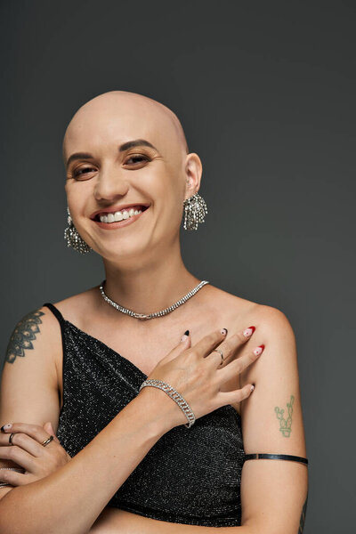 Лысая женщина с алопецией излучает уверенность, украшенная элегантными украшениями и стильной одеждой.