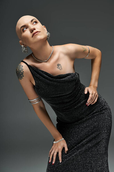 Молодая лысая женщина с облысением уверенно позирует в потрясающем, мерцающем платье.