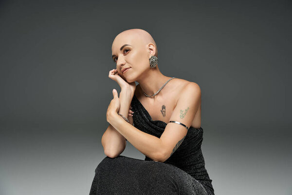 Молодая лысая женщина демонстрирует свою элегантность и силу в изящной позе, подчеркивая свою индивидуальность..