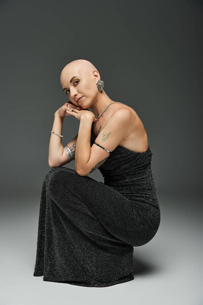 Лысая молодая женщина излучает уверенность в стильном наряде, подчеркивая свою красоту.