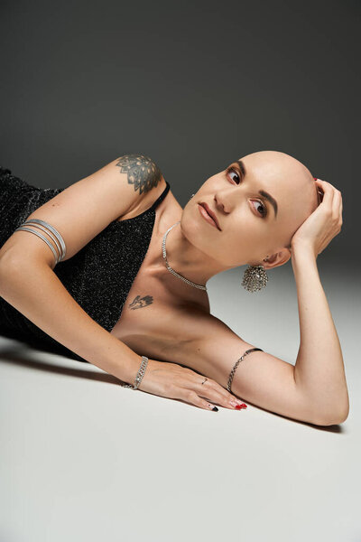 Молодая лысая женщина обнимает свою красоту, элегантно позируя на стильном фоне.