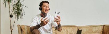 Genç adam evde canlı bir sohbete dalmış telefonuyla sohbet ederken gülümsüyor..