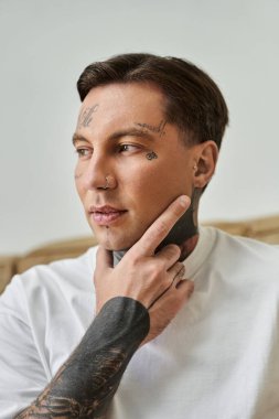 Dövmeleri olan yakışıklı adam derinden yansıyor, huzurlu ev atmosferinin tadını çıkarıyor..