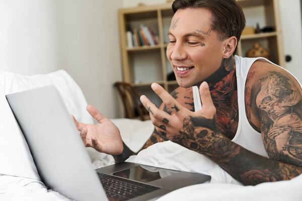 Красивый молодой человек наслаждается непринужденной беседой на своем ноутбуке, удобно расположившись дома..