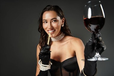 Sofistike bir kadın şarabını yudumlar ve neşeyle bir pipet tutar, zarafet ve cazibe saçar..