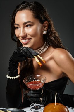 A young, beautiful woman in luxurious attire savors gourmet food and a cocktail while smiling. clipart