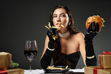 A sophisticated young woman delightfully savors gourmet food while dressed elegantly. clipart